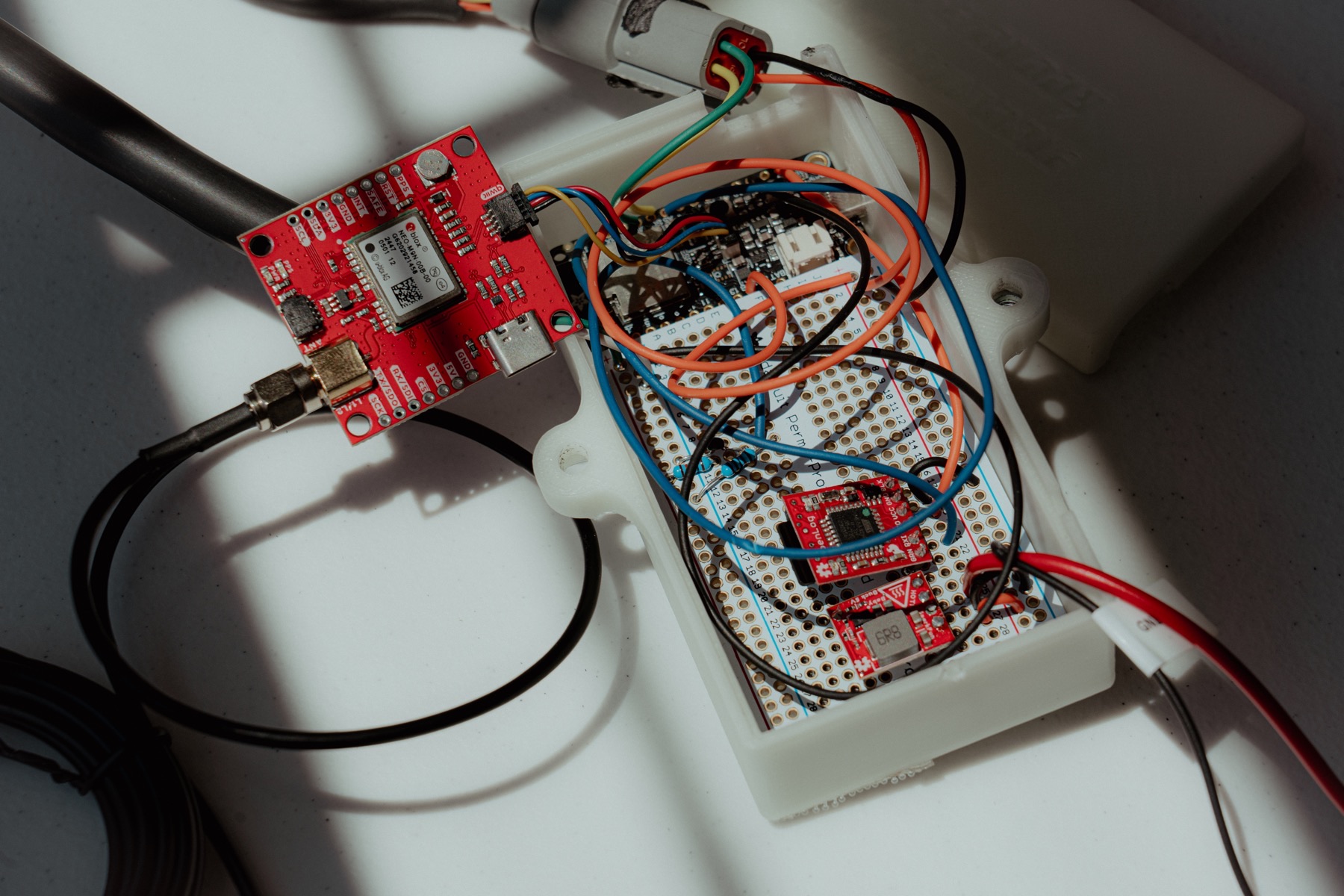 Inside the Brake Buddy prototype enclosure showing its embedded controller, GNSS module, power circuitry, and hand-built wiring