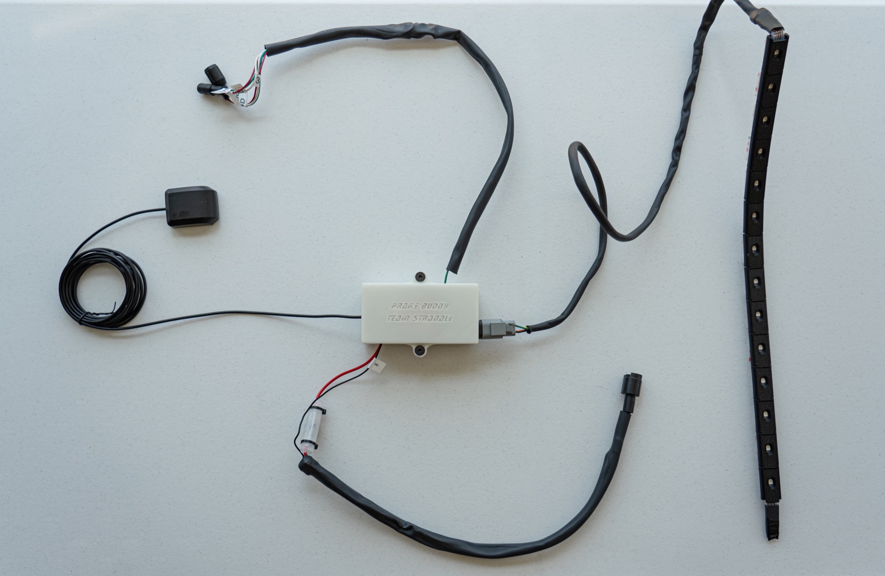 Complete Brake Buddy hardware assembly with main enclosure, GNSS antenna, vehicle harness, and LED strip